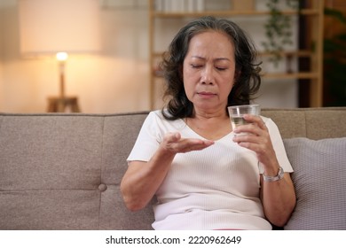 Asian Elderly Woman Taking Medicine In The Living Room At Home