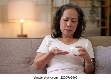 Asian Elderly Woman Taking Medicine In The Living Room At Home