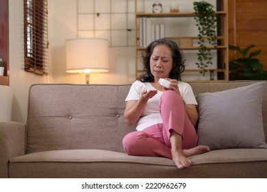 Asian Elderly Woman Taking Medicine In The Living Room At Home