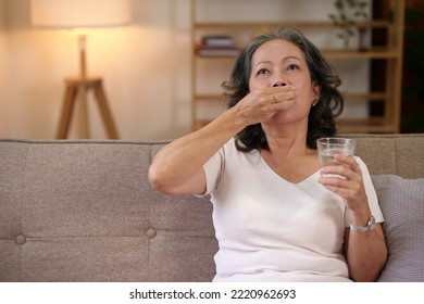 Asian Elderly Woman Taking Medicine In The Living Room At Home