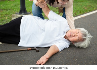 Asian Elderly Woman With Walking Stick On Floor After Falling Down,assistant Daughter Help Care To Her,sick Senior Mother Fell To The Floor Because Of Dizziness,faint,suffering From Illness In Park