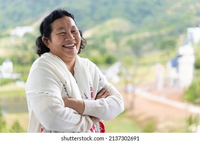 Asian Elderly Woman Wear A White Cloth Is Standing And Smiling In The Nature Background Of Green Mountain Background, Concept Of Happy And Healthy Of Senior Asian People.