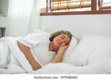 Asian Elderly woman with white hairs close eyes smile sleep and sweet dream on bed in cozy bedroom in the morning feeling so relax and comfortable,Healthcare and Sleep Concept - Powered by Shutterstock