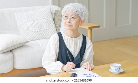 Asian Elderly Woman Writing A Letter.