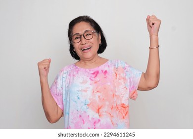 Asian elderly women cheering happily with both hand clenched in the air