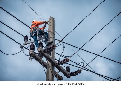 Asian electricians are climbing on electric poles to install and repair power lines. - Shutterstock ID 2193147919