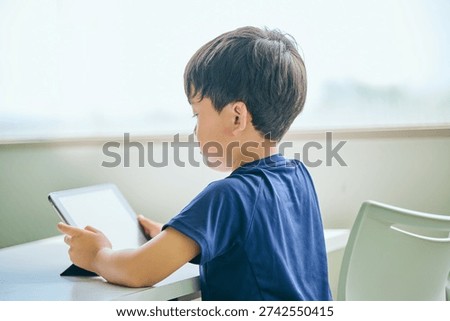Asian elementary school boy using tablet for study (back view)
