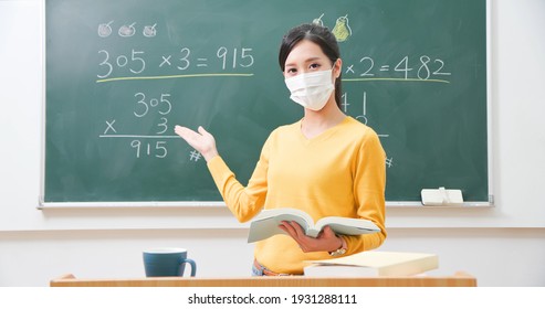 Asian Elementary School Female Teacher Wearing Face Mask Teach Math Online Through Webcam In Classroom