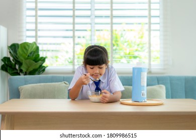 Asian Elementary School Student Girl In Uniform Eating Breakfast Cereals With Milk In Morning School Routine For Day In Life Getting Ready For School.