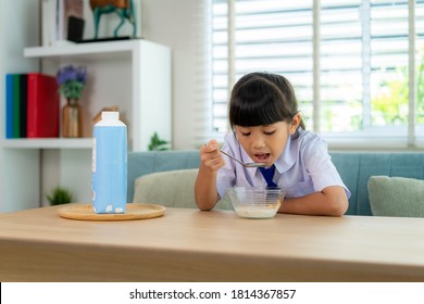 Asian Elementary School Student Girl In Uniform Eating Breakfast Cereals With Milk In Morning School Routine For Day In Life Getting Ready For School.