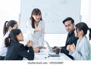 Asian Employee Presents Information And Reports. A Colleague Has A Question During A Team Brainstorming Session In A Company Meeting Room. 