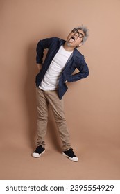 Asian energetic senior man with glasses posing  isolated on the brown background with casual clothes. mature man, Asian man. Elderly,  studio shot. Multiple emotions. - Shutterstock ID 2395554929