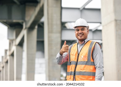 Asian engineer handsome man or architect looking construction with white safety helmet in construction site. Standing at highway concrete road site Showing thumbs up.