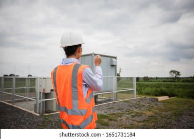 Asian engineer with hardhat using  tablet pc computer inspecting and working at wind turbine farm Power Generator Station