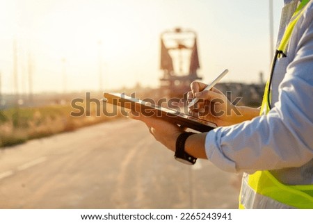 Asian engineer with hardhat using tablet pc computer inspecting and working at construction site