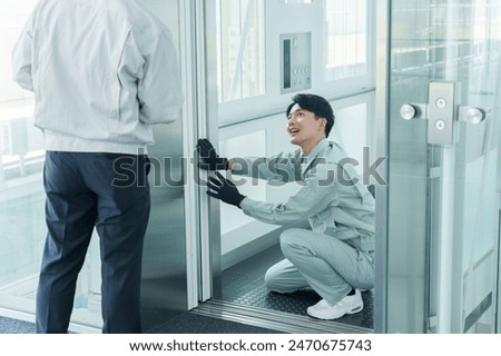 asian engineer maintaining elevator in building