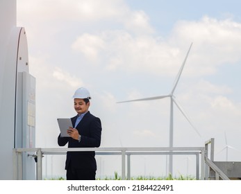 Asian engineer in a suit is using a tablet to control and monitor the operation of a wind turbine in the electrical control room.Concept of sustainability development by alternative energy