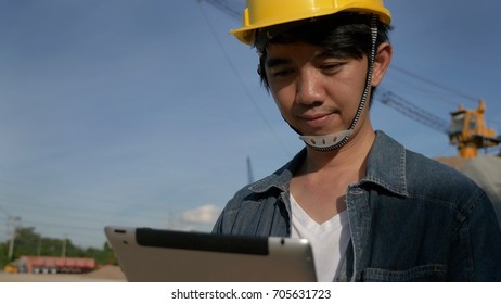 Asian Engineer using digital tablet on construction site with blue sky