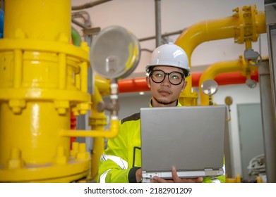 Asian Engineer Wearing Glasses Working In The Boiler Room,maintenance Checking Technical Data Of Heating System Equipment,Thailand People