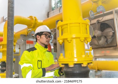 Asian Engineer Wearing Glasses Working In The Boiler Room,maintenance Checking Technical Data Of Heating System Equipment,Thailand People