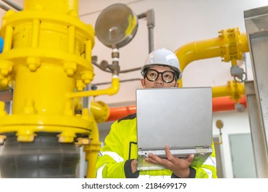 Asian Engineer Wearing Glasses Working In The Boiler Room,maintenance Checking Technical Data Of Heating System Equipment,Thailand People