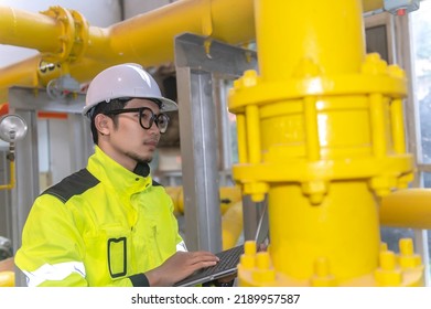 Asian Engineer Wearing Glasses Working In The Boiler Room,maintenance Checking Technical Data Of Heating System Equipment,Thailand People