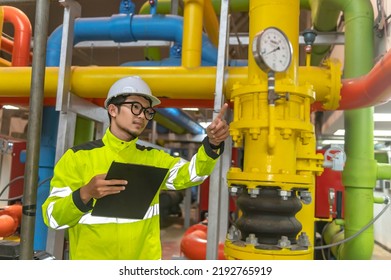 Asian Engineer Wearing Glasses Working In The Boiler Room,maintenance Checking Technical Data Of Heating System Equipment,Thailand People