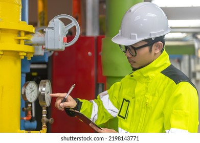 Asian Engineer Wearing Glasses Working In The Boiler Room,maintenance Checking Technical Data Of Heating System Equipment,Thailand People