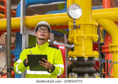 Asian Engineer Wearing Glasses Working In The Boiler Room,maintenance Checking Technical Data Of Heating System Equipment,Thailand People