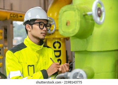 Asian Engineer Wearing Glasses Working In The Boiler Room,maintenance Checking Technical Data Of Heating System Equipment,Thailand People