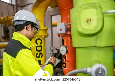 Asian Engineer Wearing Glasses Working In The Boiler Room,maintenance Checking Technical Data Of Heating System Equipment,Thailand People