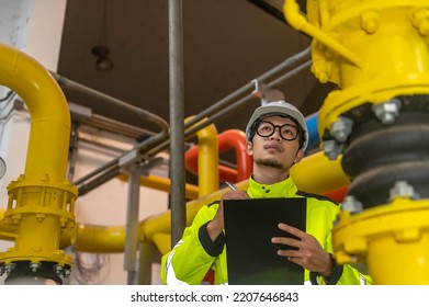 Asian Engineer Wearing Glasses Working In The Boiler Room,maintenance Checking Technical Data Of Heating System Equipment,Thailand People