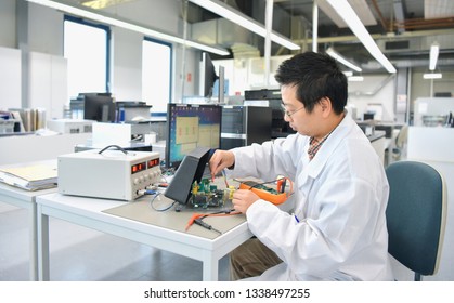 Asian Engineer At Work - Electronics Assembly And Development In A Modern Factory 