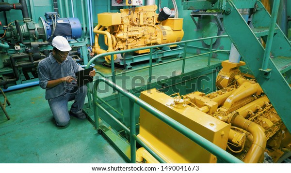 Asian engineer working in engine room. He using laptop\
in engine inspection of fishing vessel, occupation and technology\
concept 