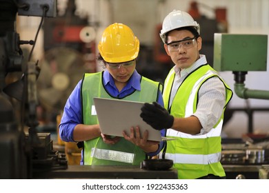 Asian Engineering Manager And Mechanic Worker In Safety Hard Hat And Reflective Cloth Using Lathe Machine Inside The Factory