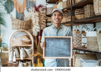 asian entrepreneur holding a blackboard standing in a handicraft shop with a handicraft background
