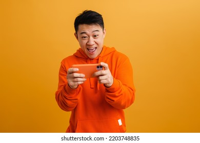 Asian excited man playing online game on mobile phone isolated over yellow background - Powered by Shutterstock