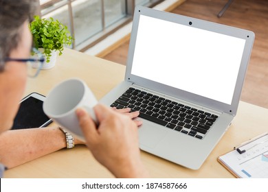 Asian Executive Senior Businessman Sitting On Desk Office With His Office, The Confident Middle Aged Handsome Man Using Laptop Computer At Workplace Home Office And Drinking A Cup Of Coffee