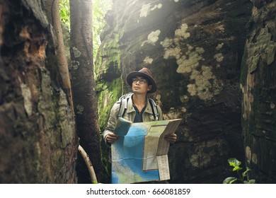 Asian explorer map travel concept, Adventure travel asian man glasses use map for survey in the forest.