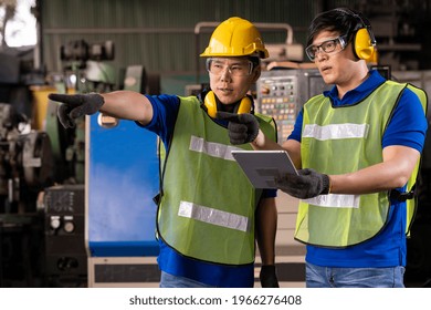 Asian factory male worker discussing and looking clipboard document for maintenance machine lathe metal in the industry factory. Engineer worker using manual document for lathe machine in the factory - Powered by Shutterstock