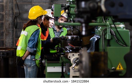 Asian Factory Worker Training To Colleague On Production Line In Heavy Industry Manufacturing Facility. Instructor With Trainee Working At Factory.