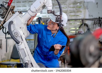 Asiatische Fabrikarbeiterin hält Tablette und Wartung mit Scheck-Teil der Robotermaschine am Arbeitsplatz. Das Industrie- und Technologieunterstützungssystem hilft bei der Arbeit des Mitarbeiterkonzepts.