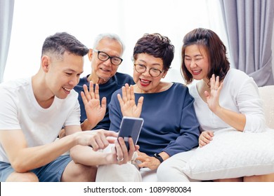 Asian Family With Adult Children And Senior Parents Making A Video Call And Waving At The Caller At Home