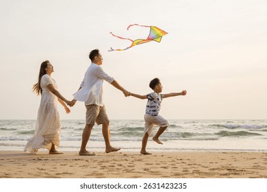 Vacaciones en la playa de la familia asiática. Los padres de los niños se relajan juntos. Personas estilo de vida. Una familia de tres está volando una cometa en la playa. El padre sostiene la cometa mientras la madre. La escena es pacífica.