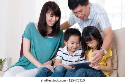 Asian Family Browsing Internet On Tablet Computer