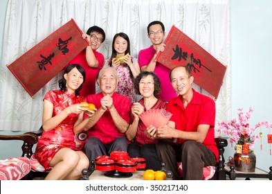 Asian Family Celebrate Chinese New Year, The Men Standing Behind Hold Bunting With The Word Of 