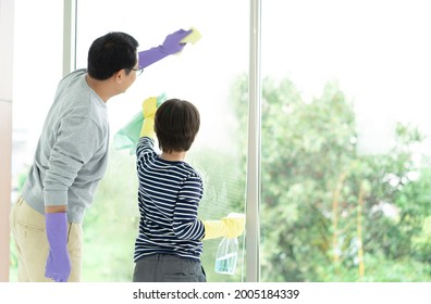 Asian Family Cleaning Day. Happy Dad And Son Cleaning Window Together On Holidays. Family Housework And Household Concept.