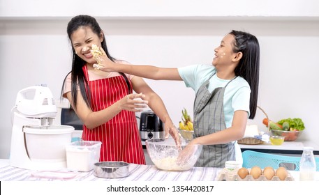 Asian family cooking food in kitchen. Happy teenage girl with her mother mixing batter in the bowl together and joyful. good team,Time of happiness. vacation holiday and Cooking together concept