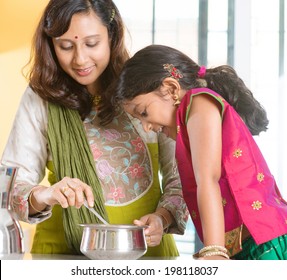 Asian Family Cooking Food Together At Home. Indian Mother And Child Preparing Meal In Kitchen. Traditional India People With Sari Clothing.