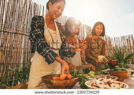 Asian family cooking thai dinner together while preparing papaya salad at home patio outdoor - Main focus on right girl face